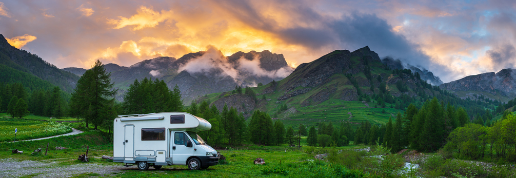 Wide shot of a class C in the mountains with sun set behind it