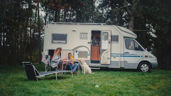 Couple with their dog outside their Class C Motorhome