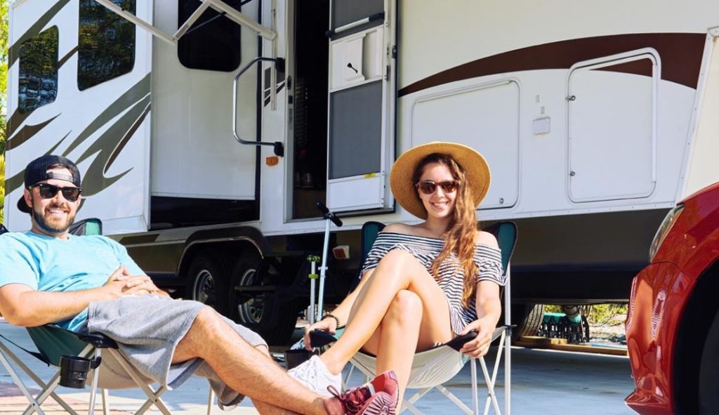 couple outside their camper in chairs