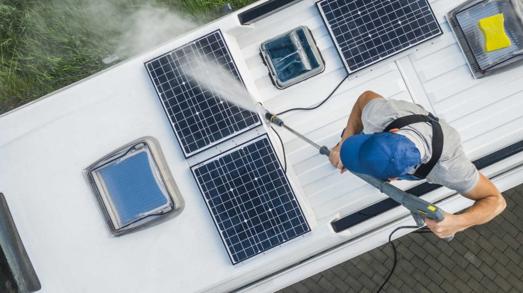 guy washing solar panels on top of rv