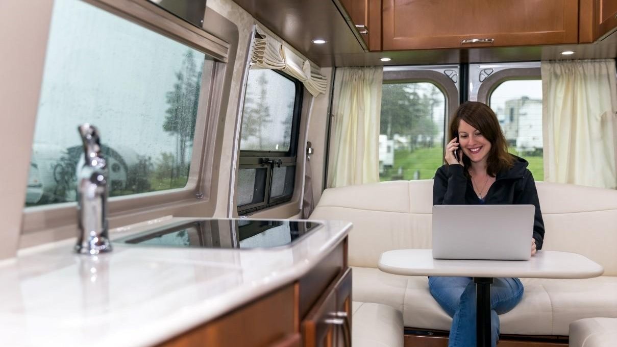 lady on cell phone with laptop in an RV