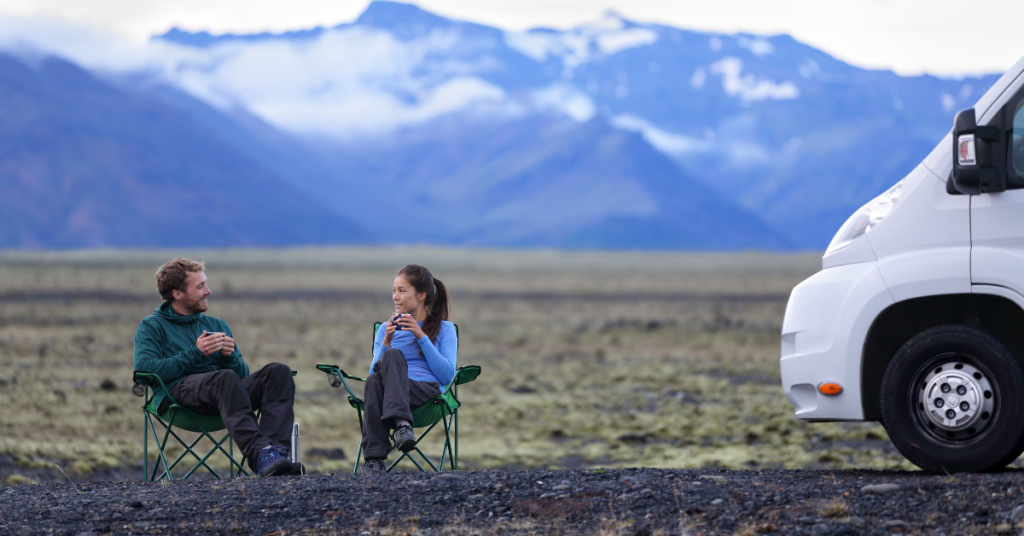 Couple drinking coffee outside next to RV