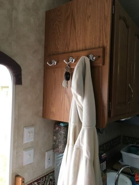 Hooks on side of kitchen cabinets near RV entry with keys and jacket hanging on hooks