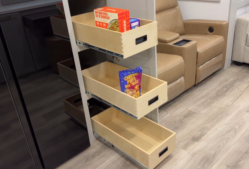 Pull-out pantry shelves in the Brinkley Model Z 2680 RV, showcasing three spacious wooden drawers, each with built-in handles, stocked with various pantry items and providing organized storage.