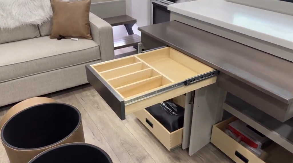 Pull-out drawer in the Brinkley Model Z 2680 RV, featuring organized compartments for efficient storage, positioned beneath a sleek countertop, with additional open storage bins visible below.