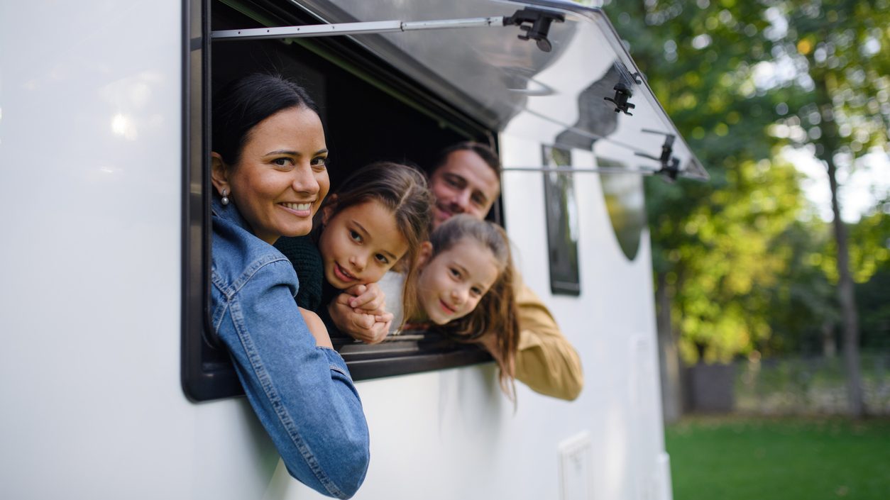 family hanging out of RV window smiling