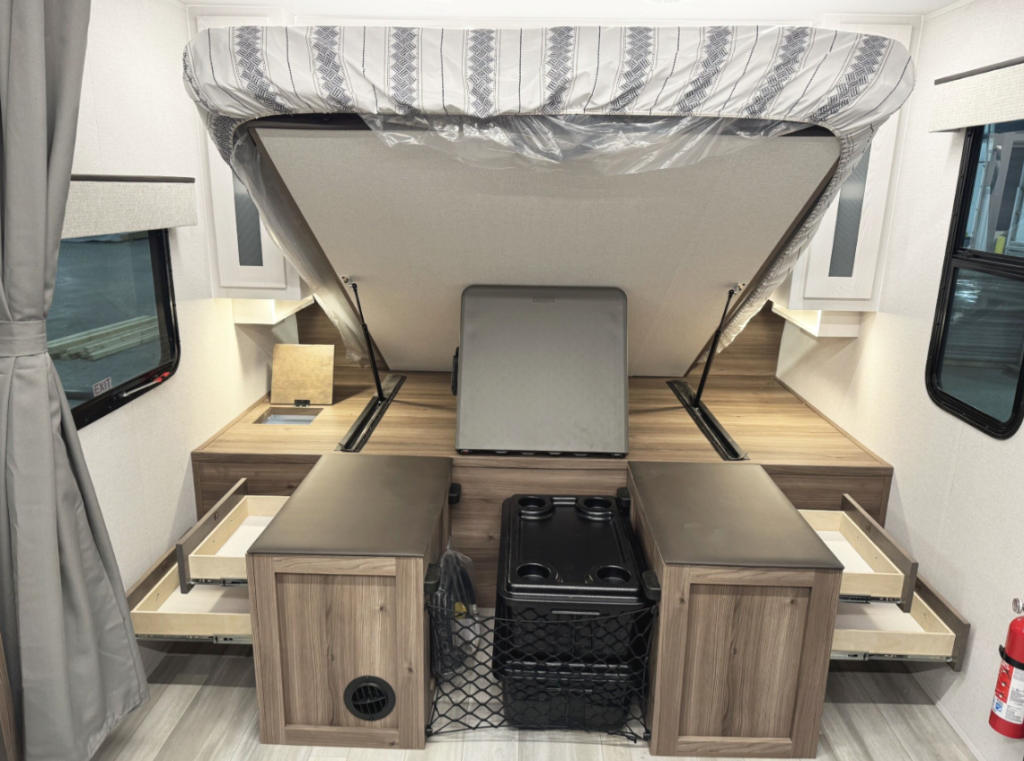 This RV setup features a versatile bed design with excellent storage solutions. The bed lifts to reveal spacious storage