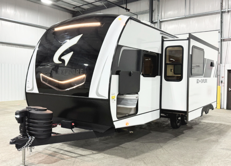 This image showcases the exterior of the GO Explore RV, featuring a sleek aerodynamic design with a large panoramic front window and an illuminated logo. The side slide-out expands the interior space for added comfort. The clean white and black color scheme enhances its modern aesthetic, making it ideal for both family trips and luxurious getaways.